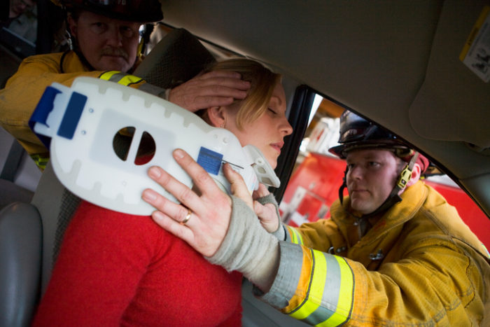 Two firemen helping woman with neck brace