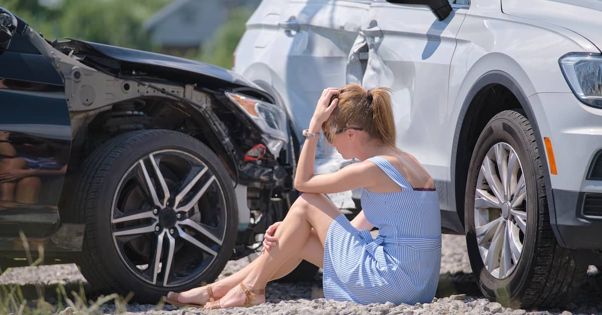 Young injured woman sitting on the ground clutching her head after an auto accident | Hauptman, O'Brien, Wolf & Lathrop