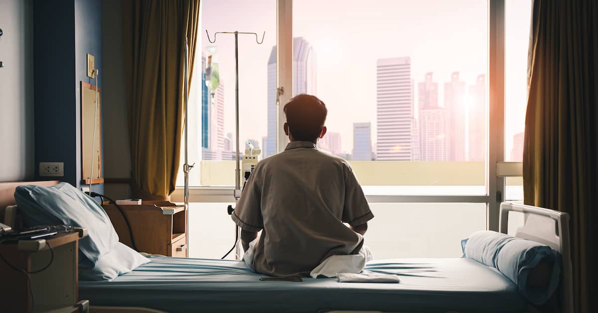 hospital patient sitting on hospital bed looking out window