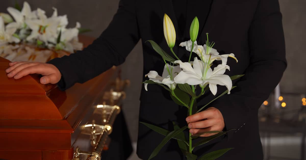 female mourner placing flower on the coffin of a deceased loved one