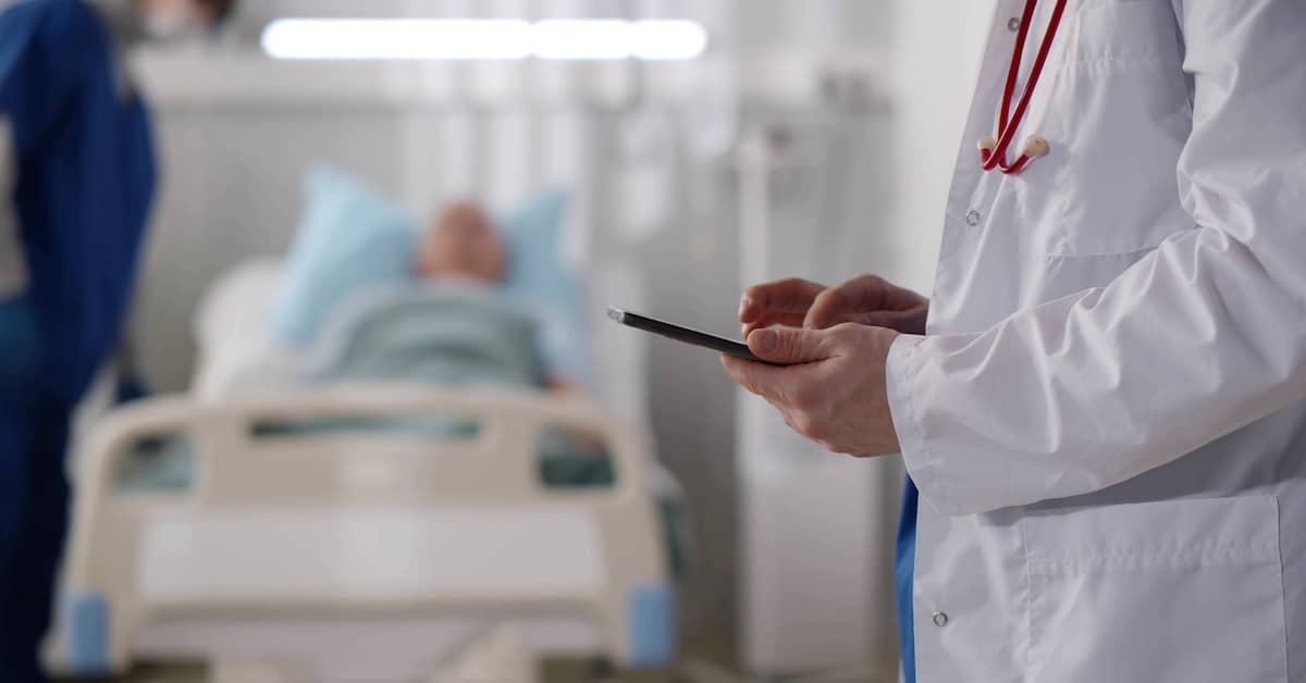 doctor reviewing chart for patient in a hospital bed