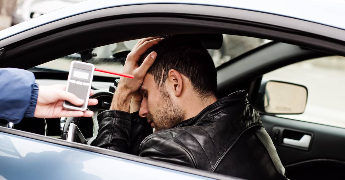 drunk driver holding his head after failing a breathalyzer test