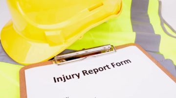hard hat sitting on clipboard holding Injury Report Form