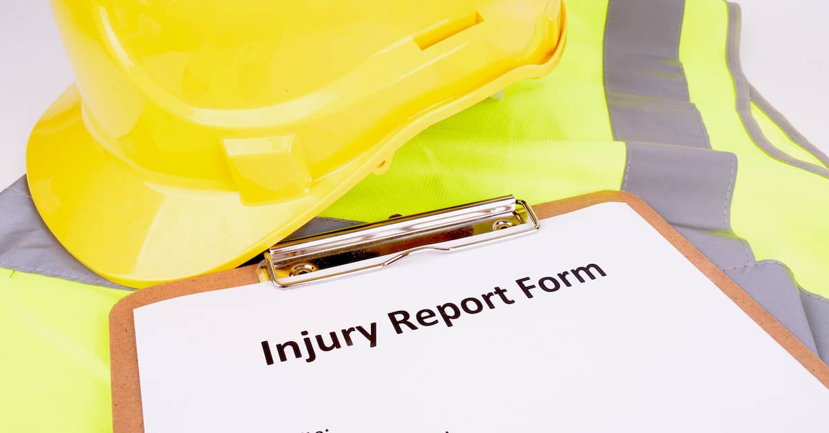 hard hat sitting on clipboard holding Injury Report Form