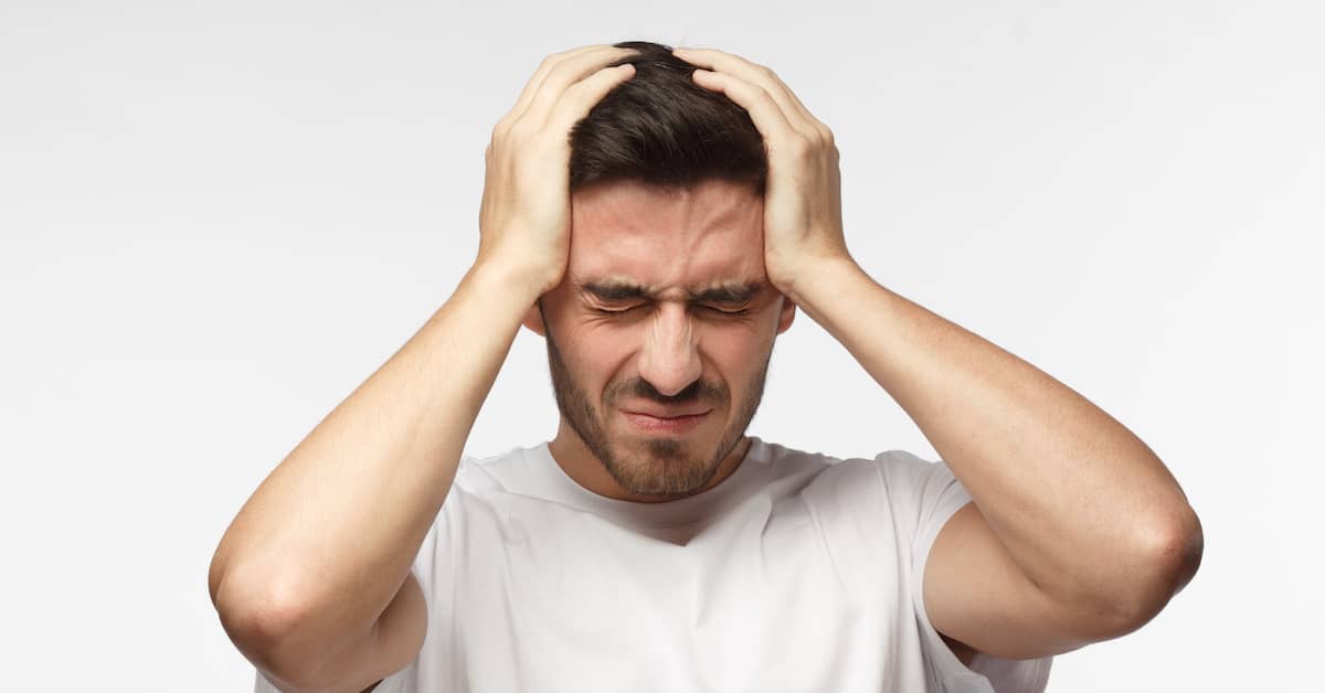 young man holding his head in pain after a brain injury