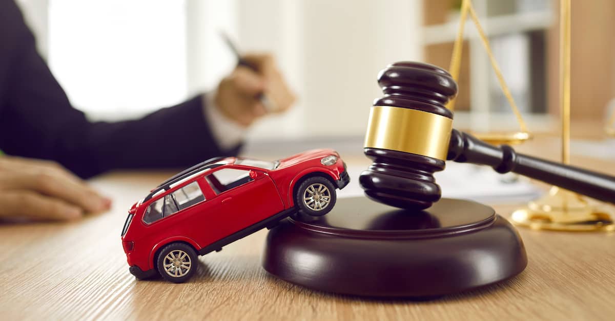 Toy car and gavel sitting on desk in front of lawyer determining if a client can sue someone after a car accident | Hauptman, O'Brien, Wolf & Lathrop