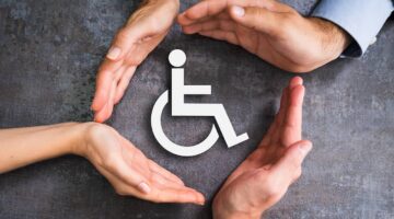 Hands enclosing a symbol for a person in a wheelchair | Hauptman, O'Brien, Wolf & Lathrop