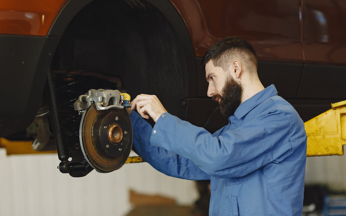 Auto mechanic working on a car's defective brake.