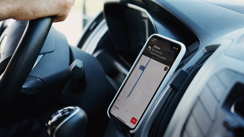 A phone placed in a car's phone holder; driver using their phone responsibly.