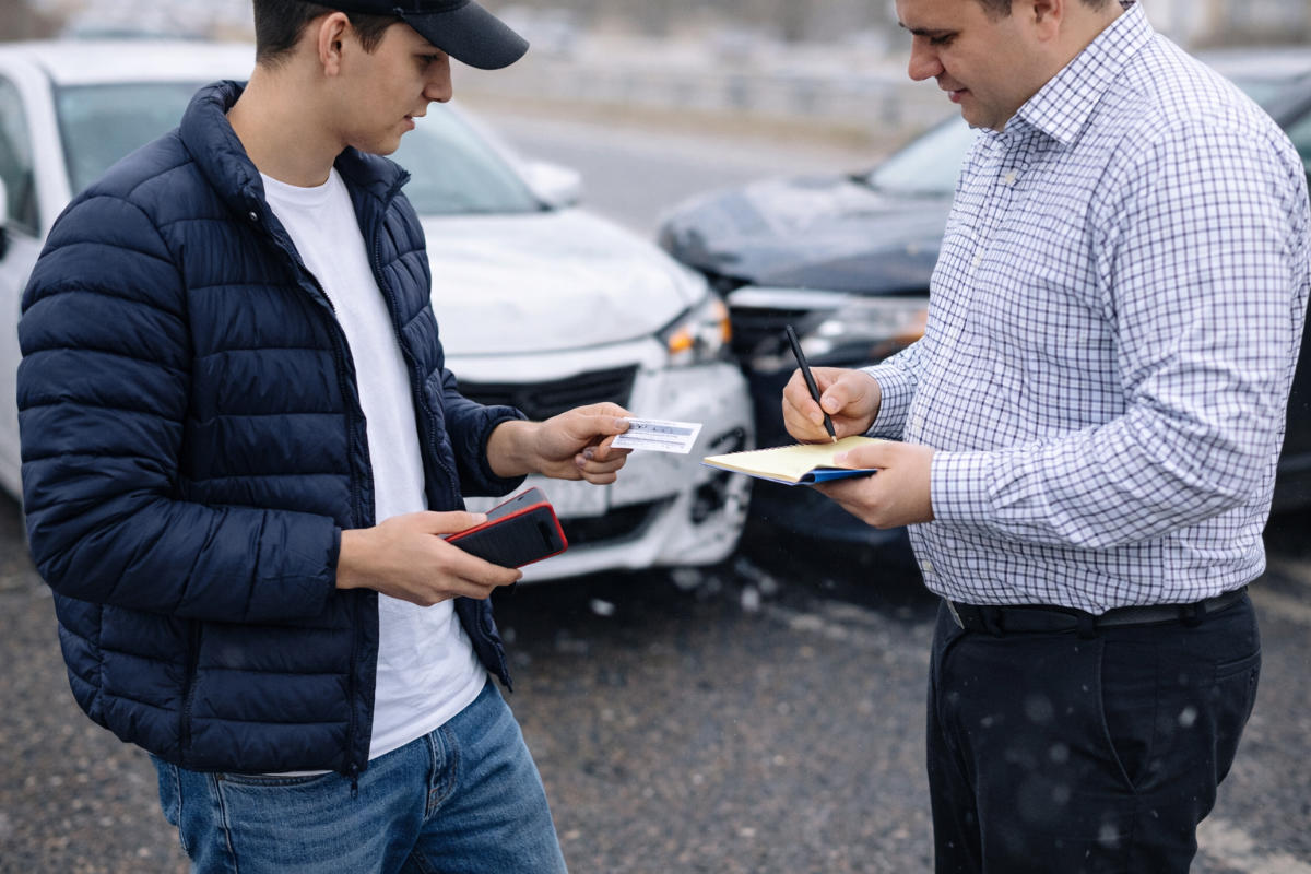 Motorists exchanging insurance and contact info after car accident.